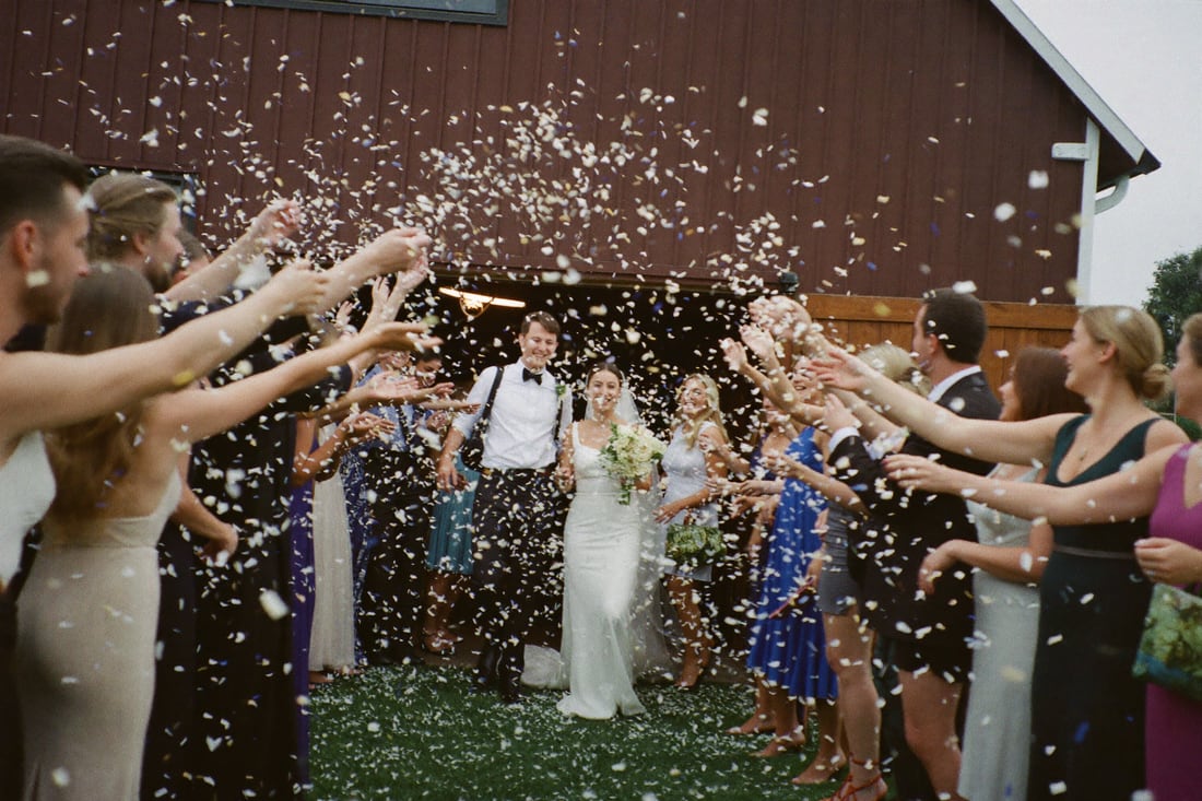 Guests throwing confetti over the couple as they leave the ceremony.