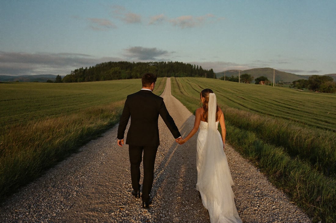 The couple walking a farm lane alone at dusk.